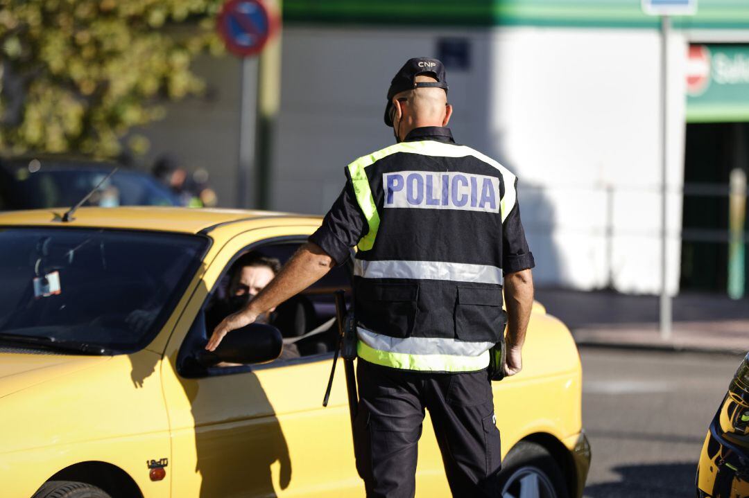 Un agente de la Policía Nacional habla con un conductor durante un control policial en una calle de Móstoles, Madrid, a 7 de octubre de 2020