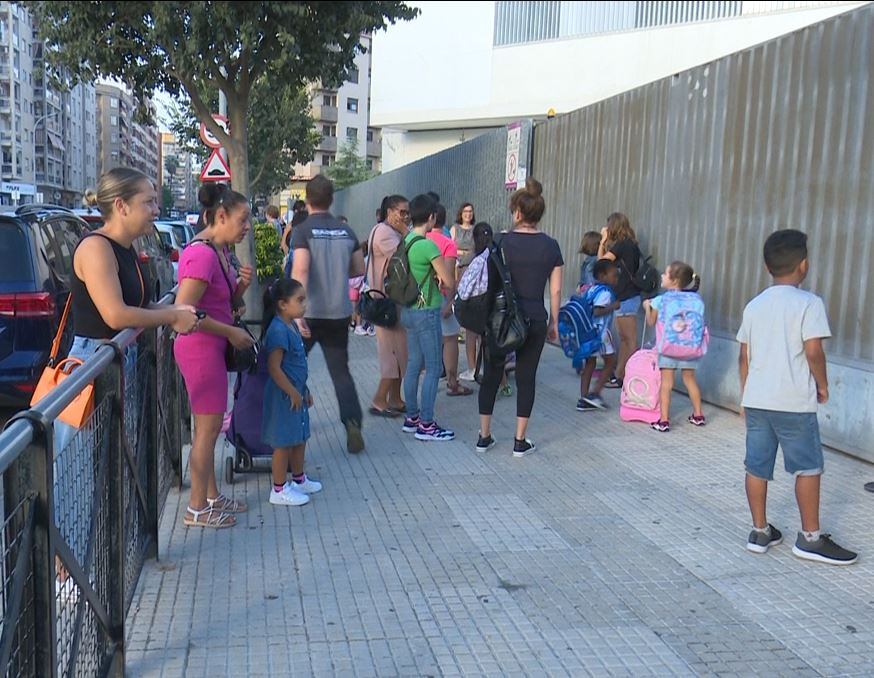 Un grupo de padres y madres llevan a sus hijos en el primer día de colegio en Gandia.