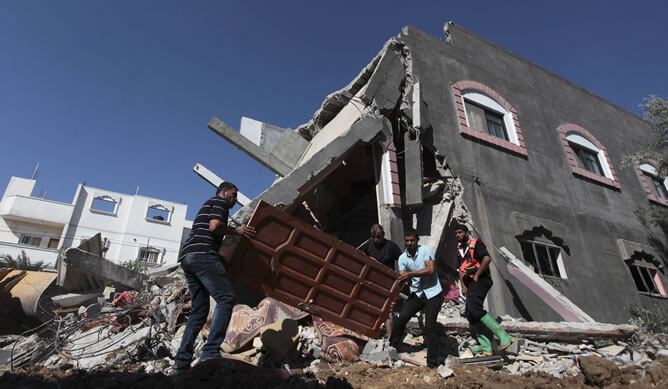 Palestinos ante una casa destruida tras un ataque aéreo israelí en el centro de la Franja de Gaza.