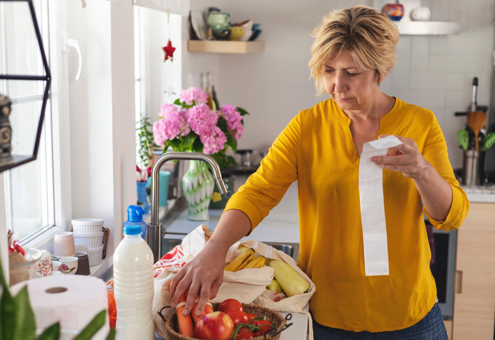 Una mujer comprueba la compra en la cocina (Sladic/Getty).