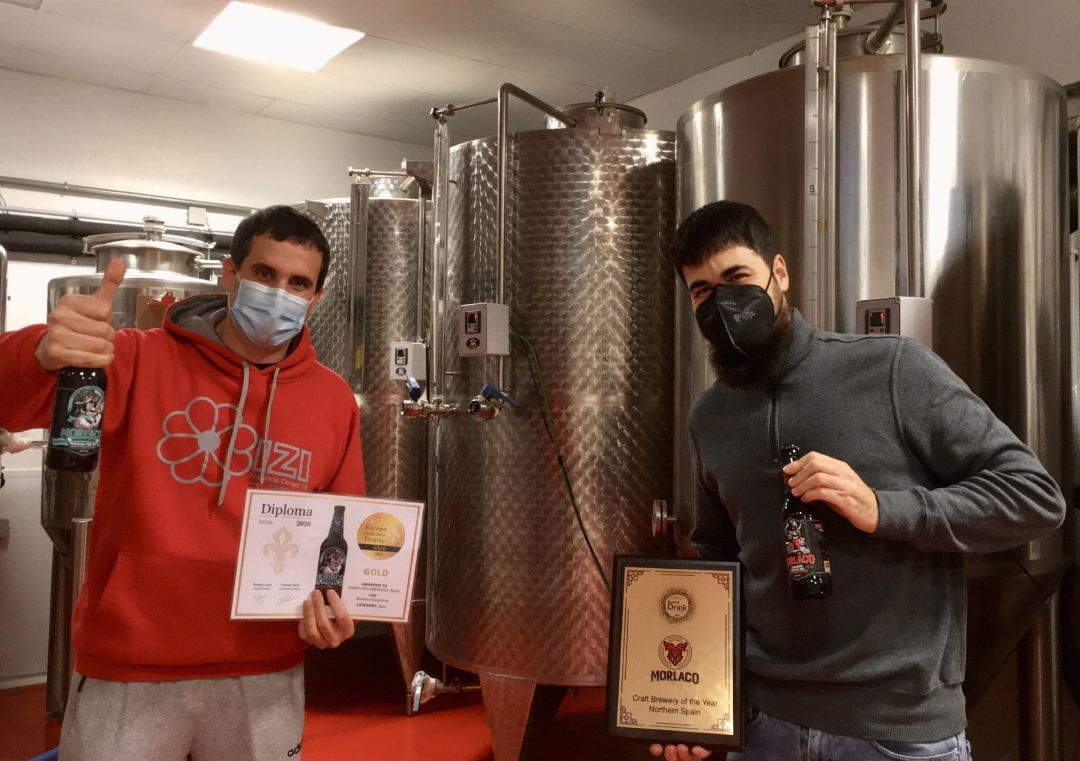 Asier Aguirre Lecea y David Salinas Lizaso, los dos socios y fundadores de Pamplona Brewing SL, con los dos premios recibidos en la sala de fermentadores que tienen en sus instalaciones 