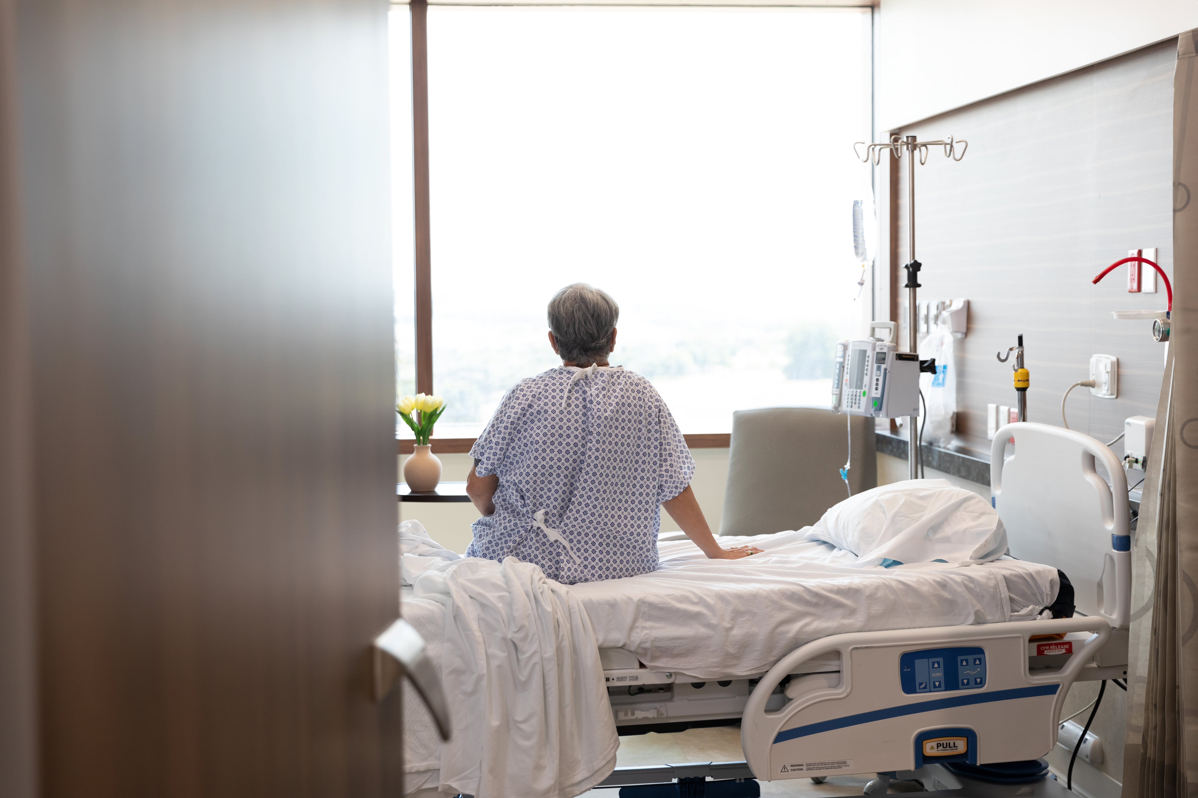 Una paciente permanece sentada en la cama de un hospital.