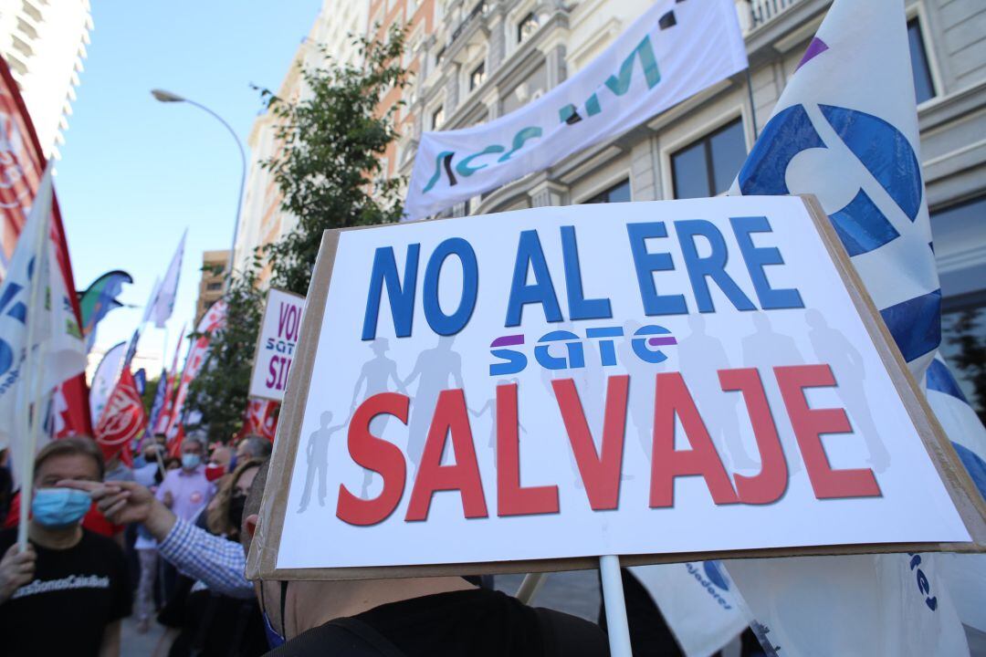 Un trabajador de CaixaBank sostiene una pancarta donde se puede leer &quot;No al ERE salvaje&quot; durante el paro parcial convocado para protestar por el ERE de la entidad financiera, a 7 de junio de 2021, en Madrid