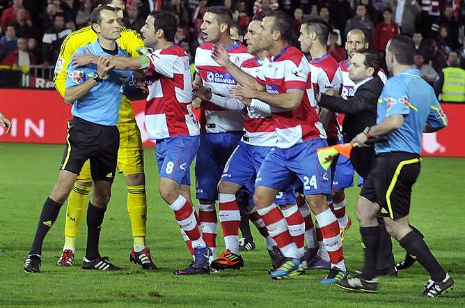 El árbitro Carlos Clos Gómez es asediado por los jugadores del Granada antes de recibir un botellazo al final del partido, correspondiente a la trigésimo séptima jornada de Liga de Primera División