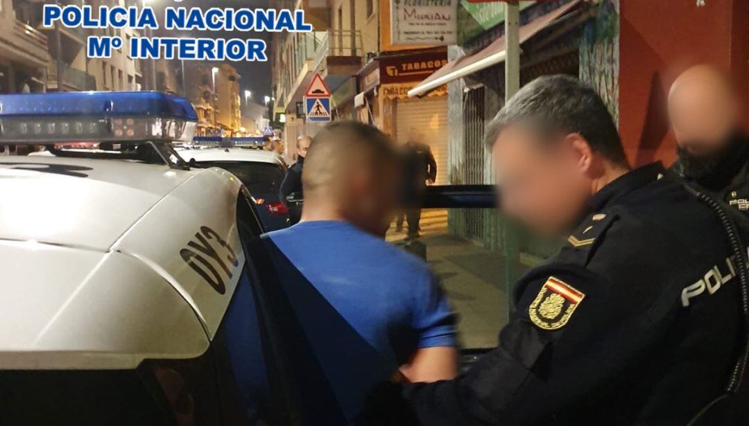 Un agente introduce en el coche patrulla a uno de los dos detenidos