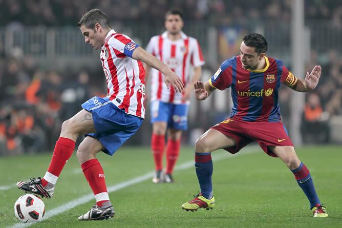 El defensa del Atlético de Madrid Antonio López (i) controla el balón ante el centrocampista del F.C.Barcelona Xavi Hernández, en partido correspondiente a la vigésimo segunda jornada de Liga en Primera División que se disputa en el Camp Nou.