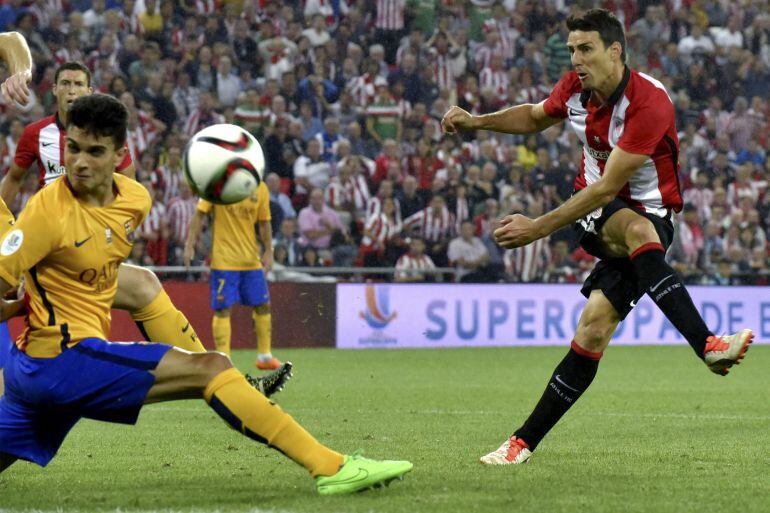 El delantero del Athletic, Aritz Aduriz (d), golpea el balón consiguiendo el tercer gol del equipo bilbaino, durante el encuentro correspondiente a la ida de la supercopa que disputan esta noche frente al F. C. Barcelona en el estadio de San Mamés, Bilbao