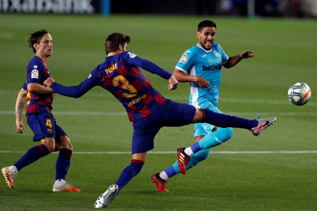 El defensa del FC Barcelona, Gerard Piqué (c), despeja el balón ante el centrocampista del CD Leganés, Recio