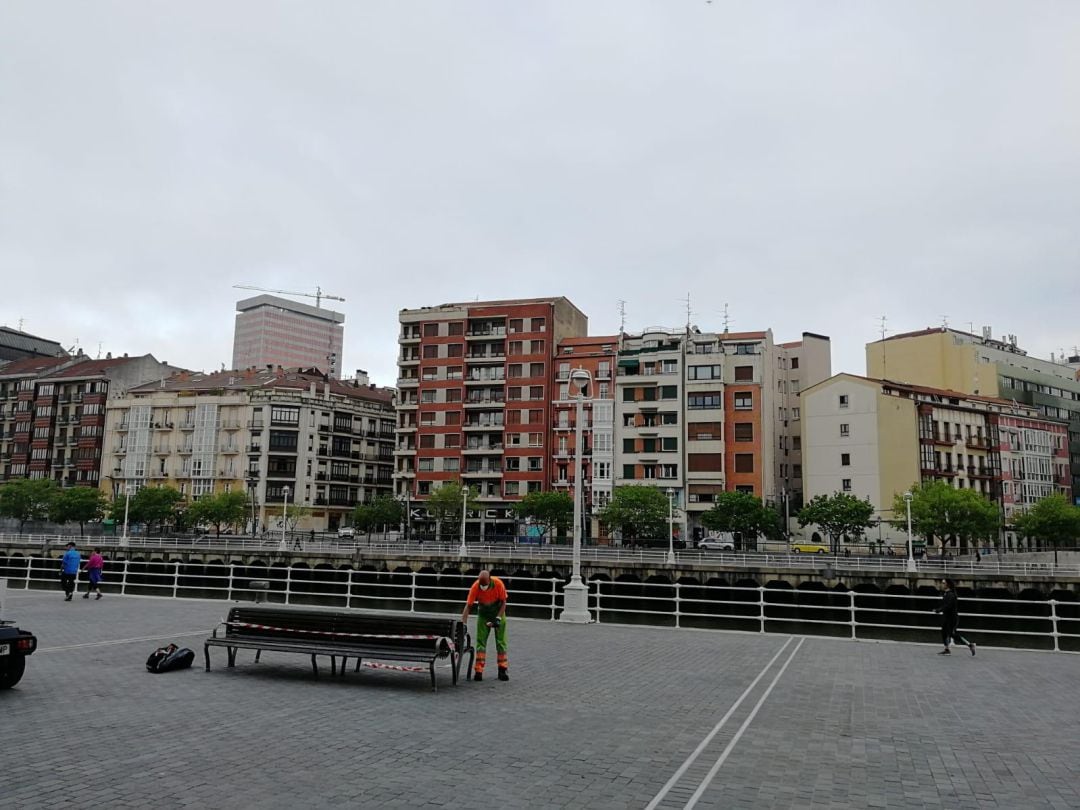 Un operario higienizando un banco en el paseo de la ría