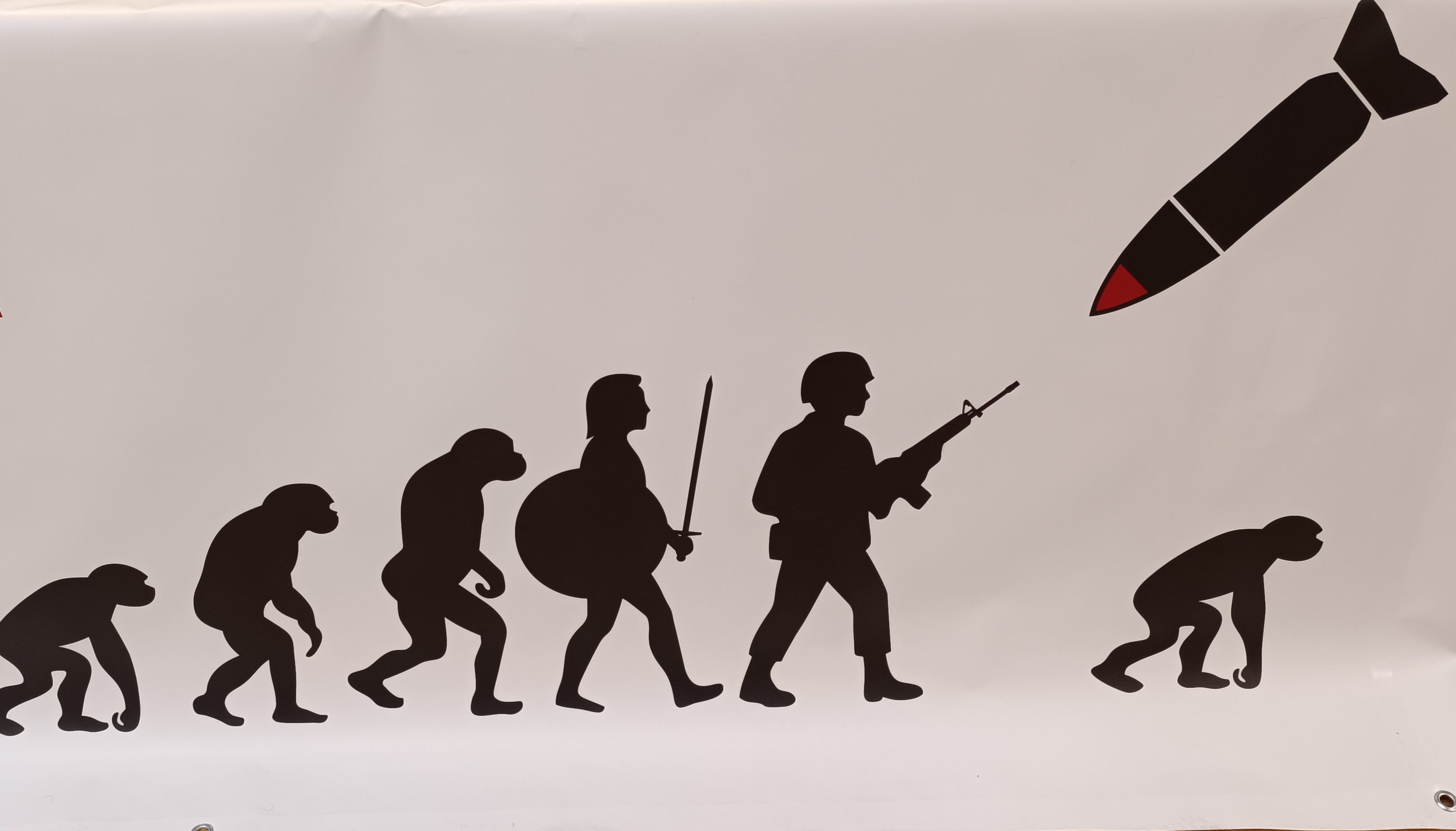 El cartel de la protesta contra el rearme simboliza el retroceso de la evolución humana que suponen las guerras