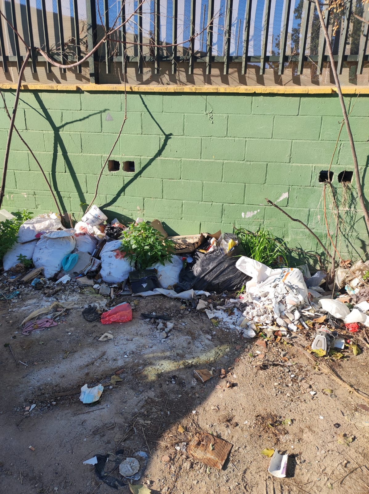 Basura, suciedad y desperfectos en la pared del patio del colegio Hernández Cánovas de Tiro Pichón de Málaga