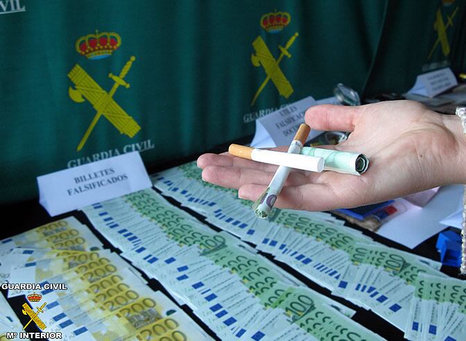 Un agente de la Guardia Civil muestra el sistema que usaban los falsificadores para introducir los billetes.