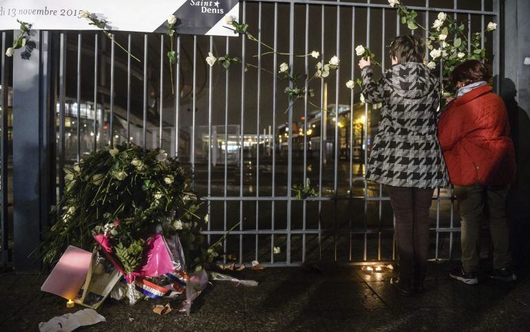 Varias personas depositan flores en homenaje a las víctimas de los atentados perpetrados por el Estado Islámico (EI) el pasado viernes, en el Estadio de Francia, en Saint Denis, Francia