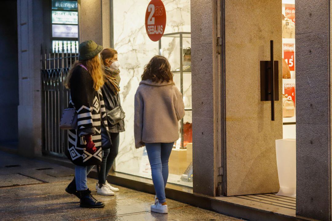 Varias personas en el exterior de un comercio en una jornada marcada por el inicio de la entrada en vigor de una desescalada gradual.