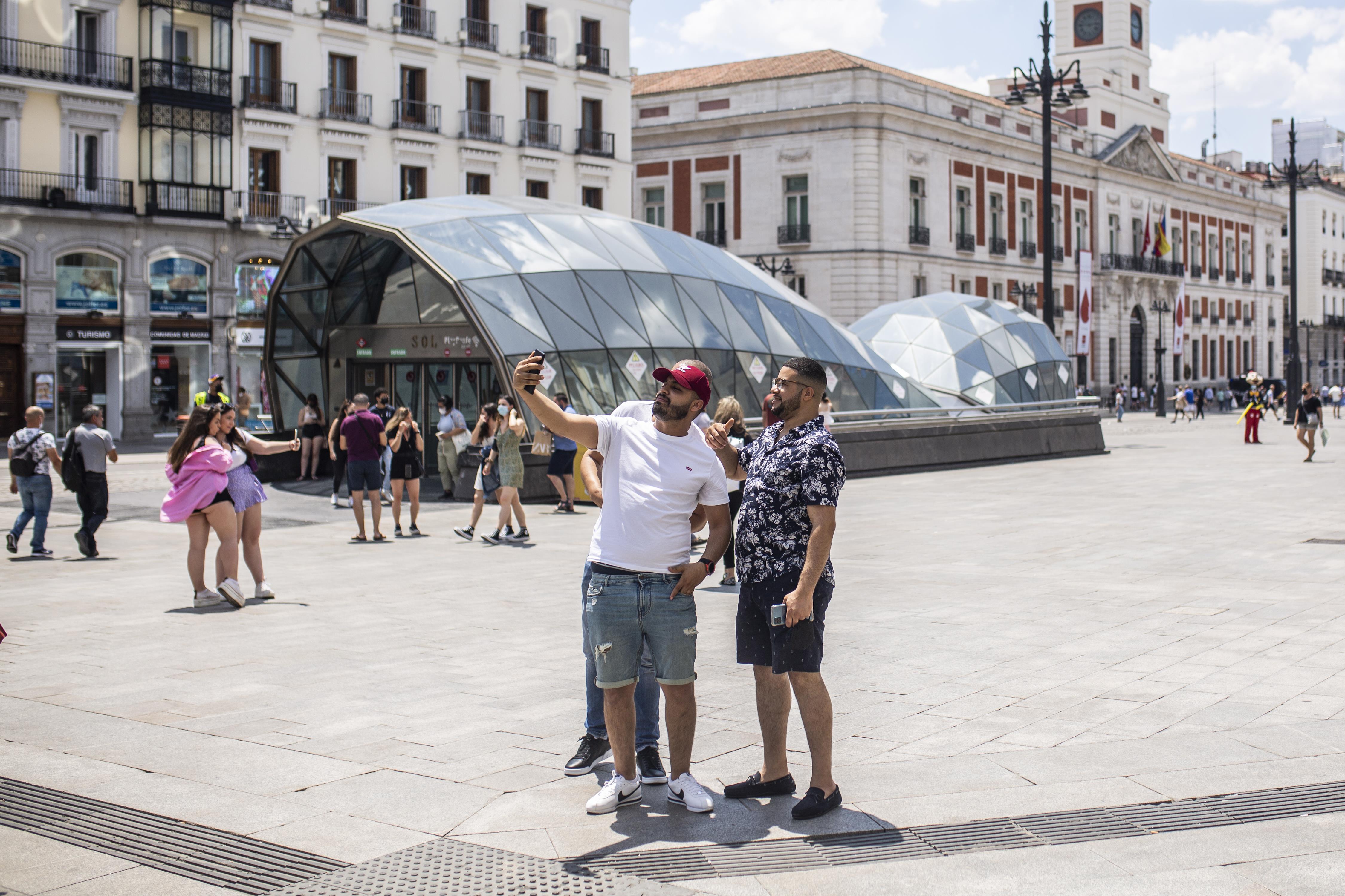 Tres personas posan delante de la &#039;ballena&#039; para entrar a Cercanías en la Puerta del Sol, el pasado junio de 2021.