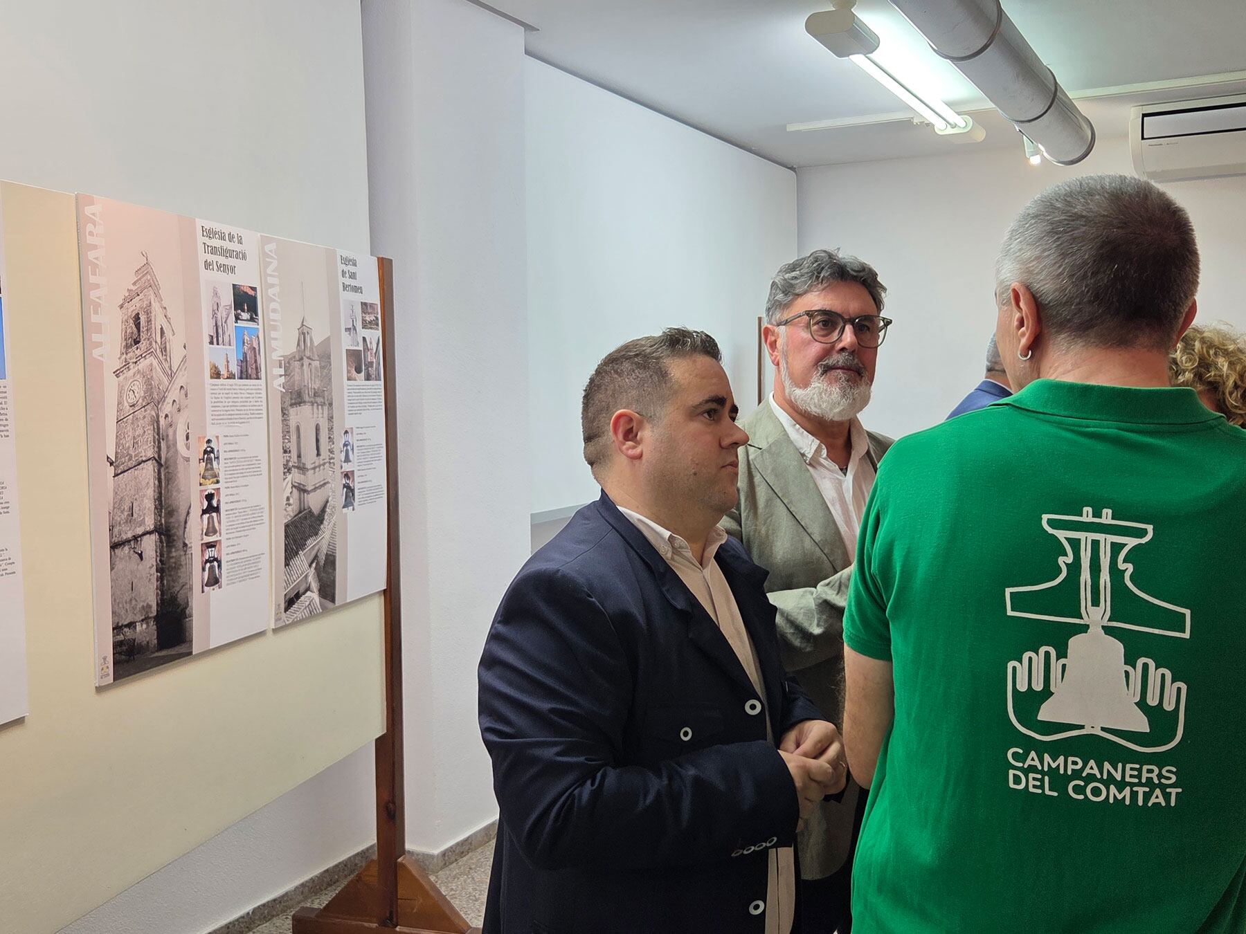 Vicent Molina i Saúl Serrano conversant en un dels components de Campaners de El Comtat en l'exposició dels campanars de les poblacions d'aquesta comarca