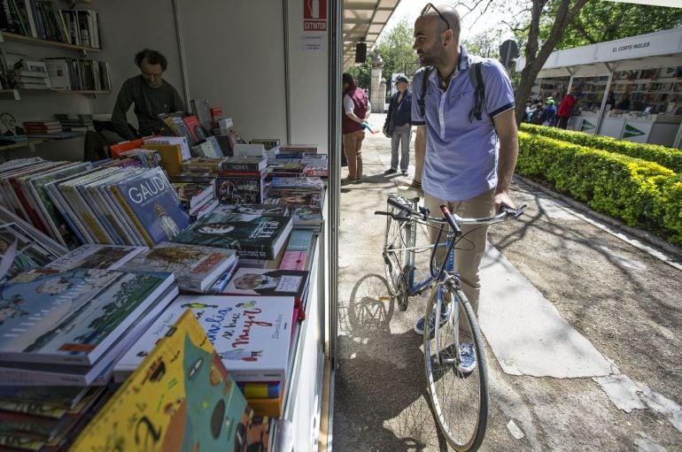 Un joven observa los libros expuestos en una caseta de la Feria del Libro de Valencia cuya quincuagésima edición se ha inaugurado este mediodía en los Jardines de Viveros