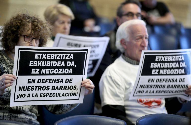 Representantes de varias plataformas de ciudadanos protestan con carteles en el Salón de Plenos del Ayuntamiento de San Sebastián. 