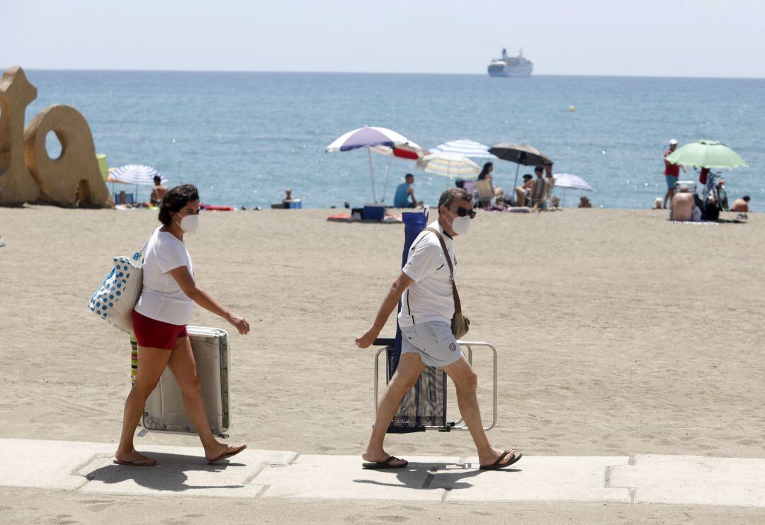 Dos personas con mascarilla acceden a la playa de La Malagueta. En Málaga (Andalucía, España), a 19 de julio de 2020.