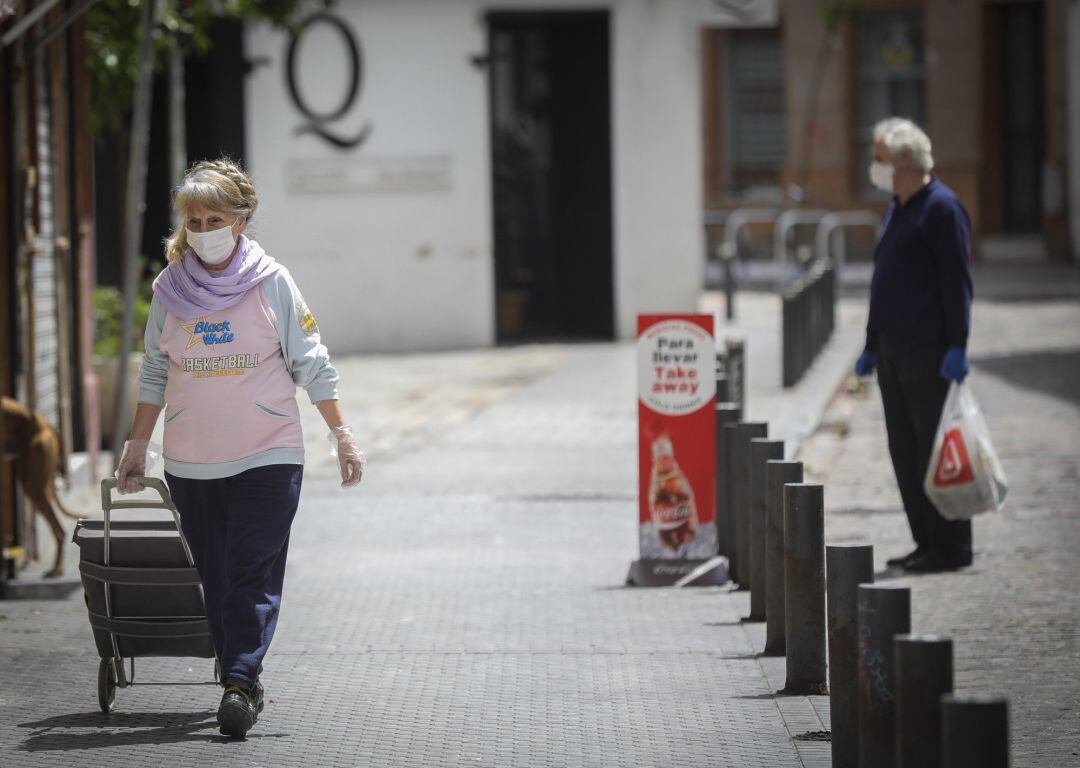 Una mujer con mascarilla, guantes y un carrito de la compra camina por el barrio de la Alameda, durante el día 38 del estado de alarma en el país por la crisis del coronavirus. 