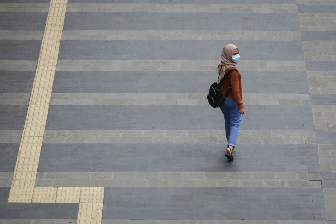 Una mujer pasea con mascarilla por las calles de Yakarta, Indonesia