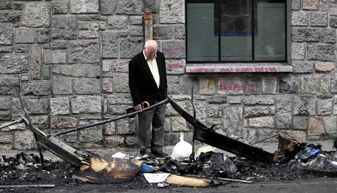 Un hombre mira los restos del incendio provocado por unos desconocidos, que han quemado esta madrugada en Andoain (Gipuzkoa) cuatro contenedores, lo que ha obligado a desalojar un edificio, cuya fachada ha resultado afectada por las llamas