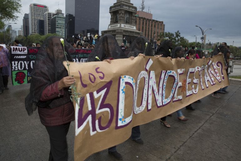 Protesters hold a banner as they march toward the central square, known as the Zocalo, to protest at the government&#039;s response to the mass disappearance of 43 college students in Mexico City, Mexico, on Thursday, Nov. 20, 2014. Evidence in the missing stu