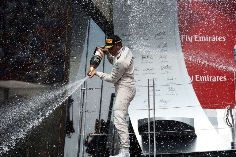 Mercedes AMG Petronas British driver Lewis Hamilton sprays champange on his teammates from the podium at the Circuit Gilles Villeneuve in Montreal on June 7, 2015, after winning the Canadian Formula One Grand Prix. AFP PHOTO/JEWEL SAMAD