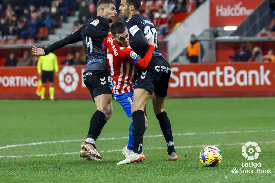 Víctor Campuzano cae en el área entre dos jugadores del Málaga.