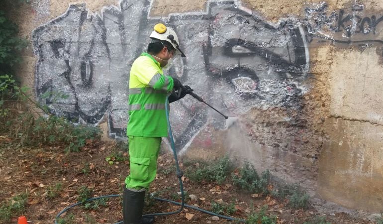 Operari netejant una paret pintada.