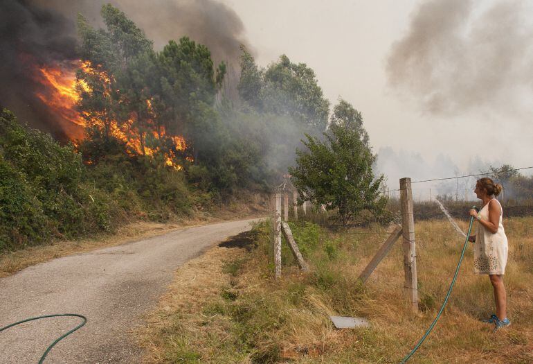 Una mujer observa como llegan a las casas de la zona de Sela las llamas del incendio forestal de Arbo (Pontevedra), en el que se ha decretado la Situación 2, por la cercanía del fuego a núcleos de población. Las hectáreas de monte afectadas por los incend