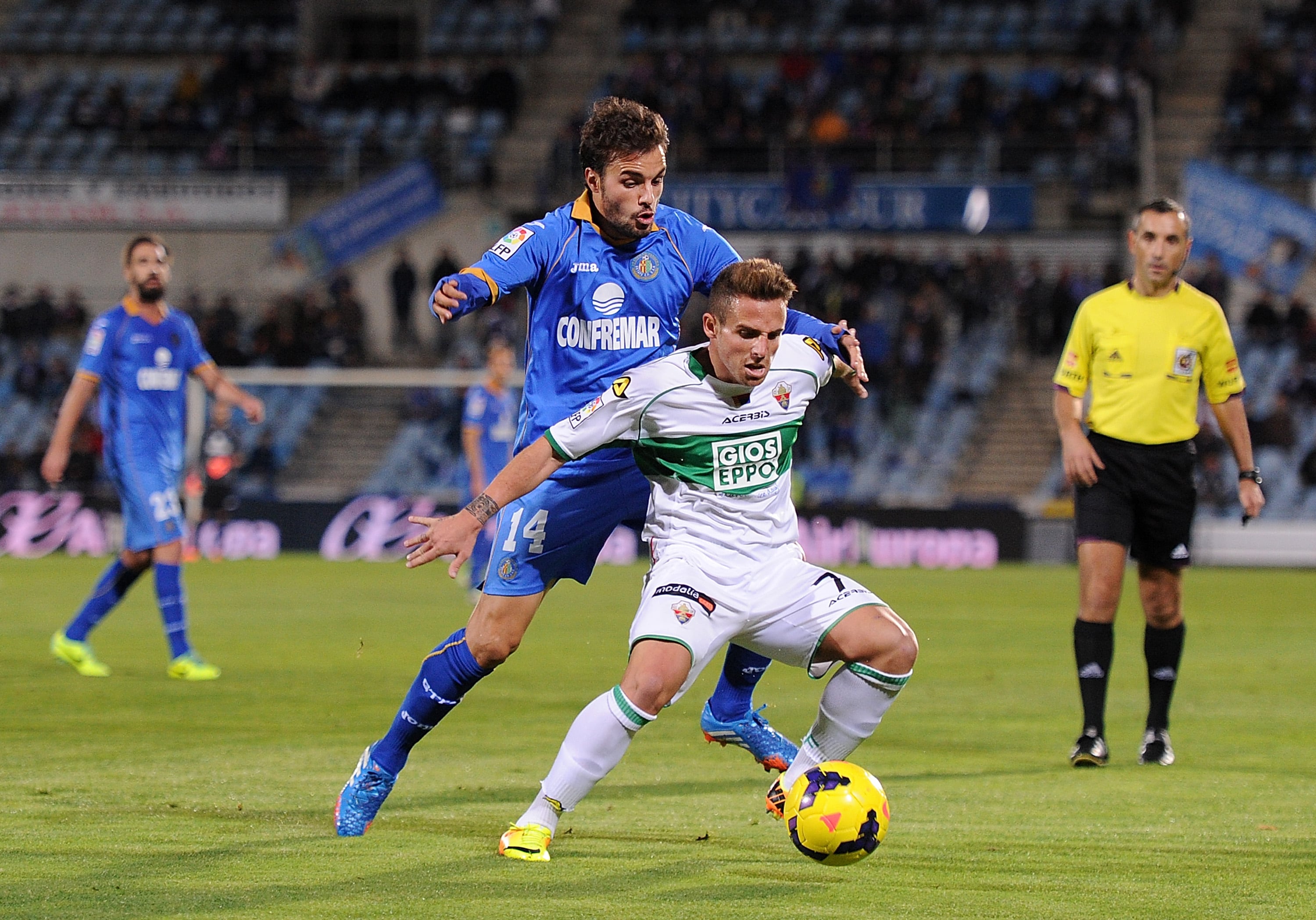 Aaron Ñíguez, con la camiseta del Elche, defiende un balón ante Pedro León, en 2013