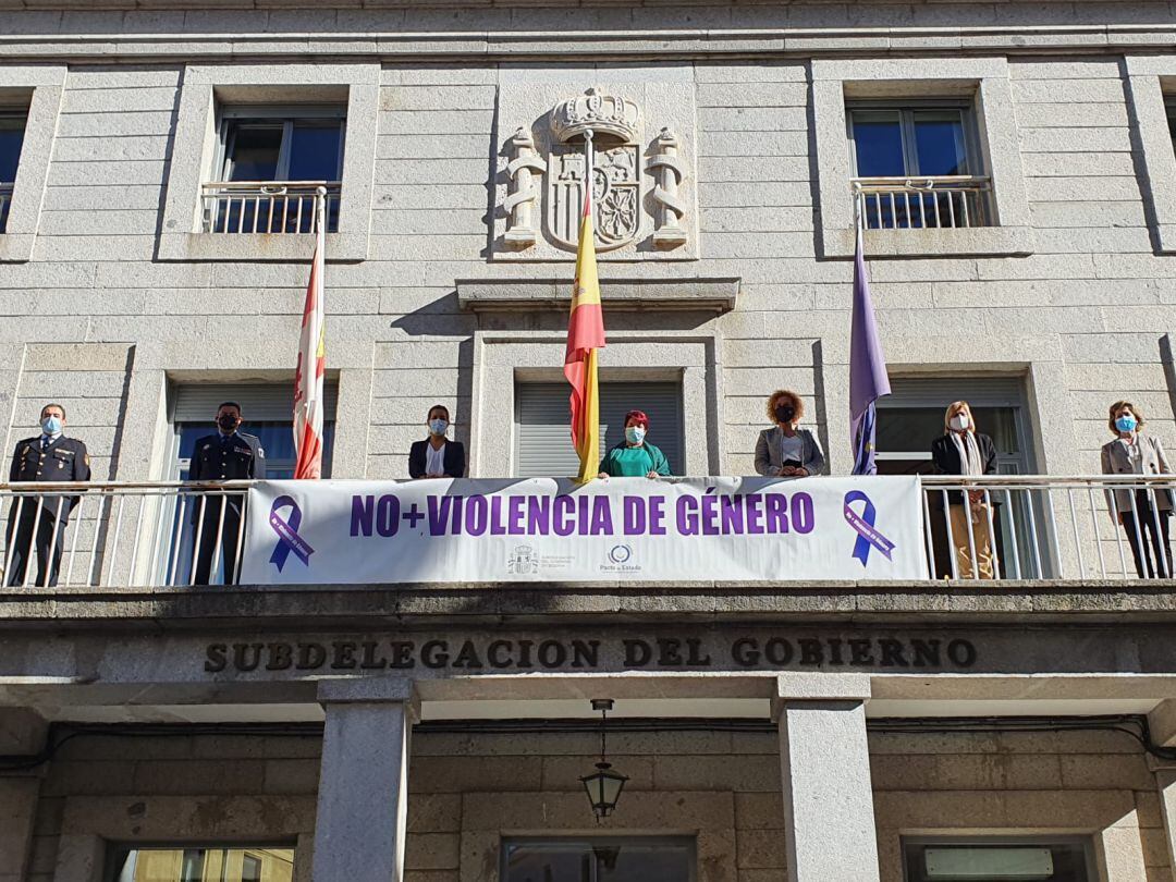Representantes de la Subdelegación del Gobierno y del Ayuntamiento de Segovia posan con la pancarta desplegada en el balcón de la Subdelagación