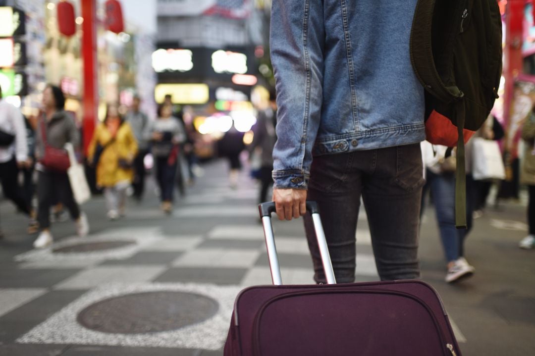 Imagen de archivo de un joven con su maleta