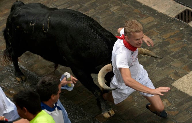 Un corredor es atrapado entre los cuernos de un toro de la ganadería Fuente Ymbro en la calle Santo Domingo