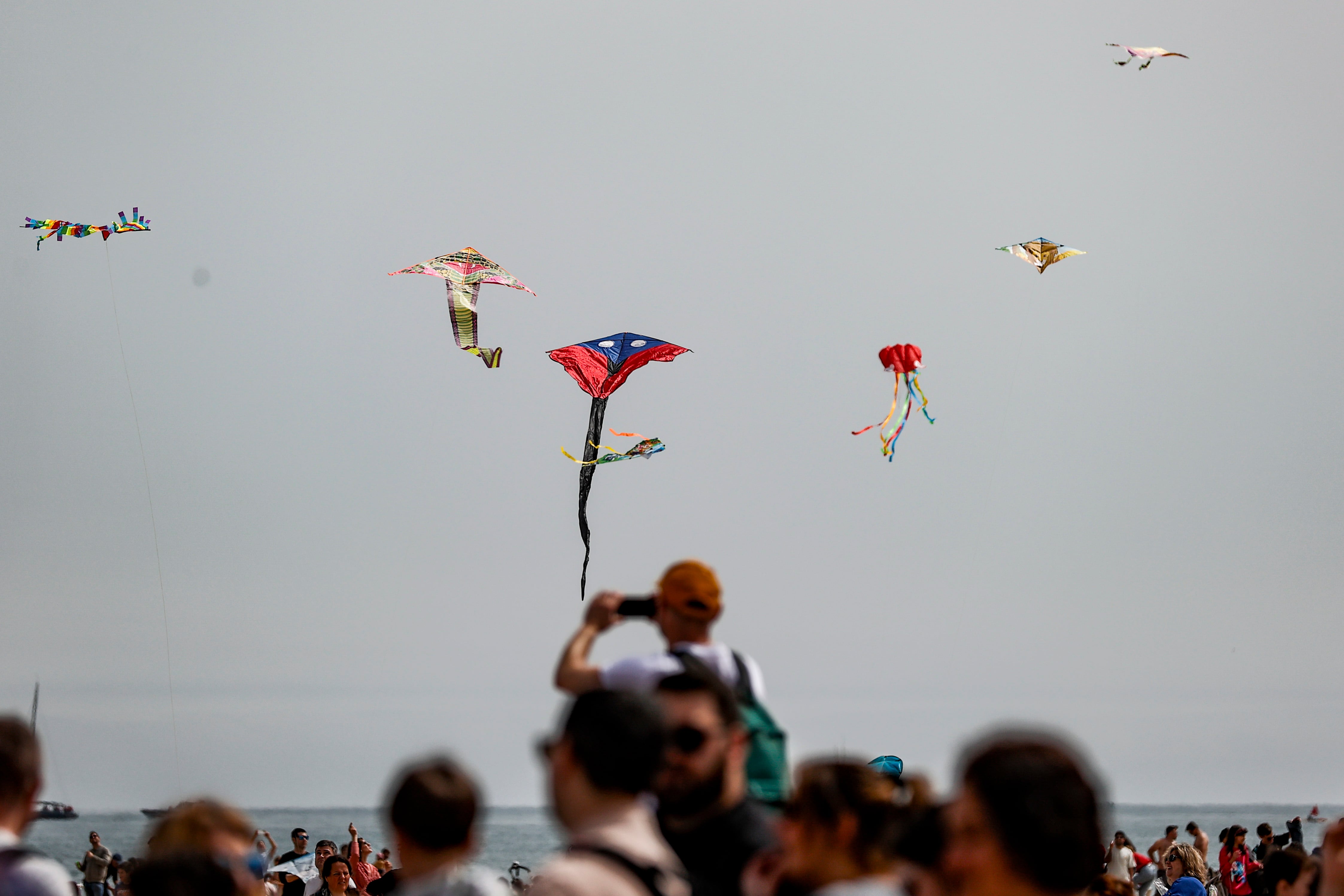 VALÈNCIA, 06/04/2024.- Un hombre toma una fotografía de las cometas que han conseguido alzar el vuelo pese al escaso viento este sábado en la playa de Las Arenas donde se celebra el XXIII Festival de Cometas Ciudad de València. EFE/Manuel Bruque