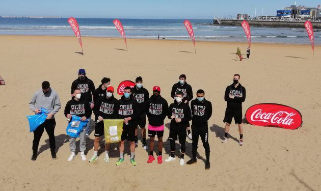 La plantilla del Círculo Gijón Baloncesto en la playa de San Lorenzo durante la recogida de residuos organizada por Coca-Cola.