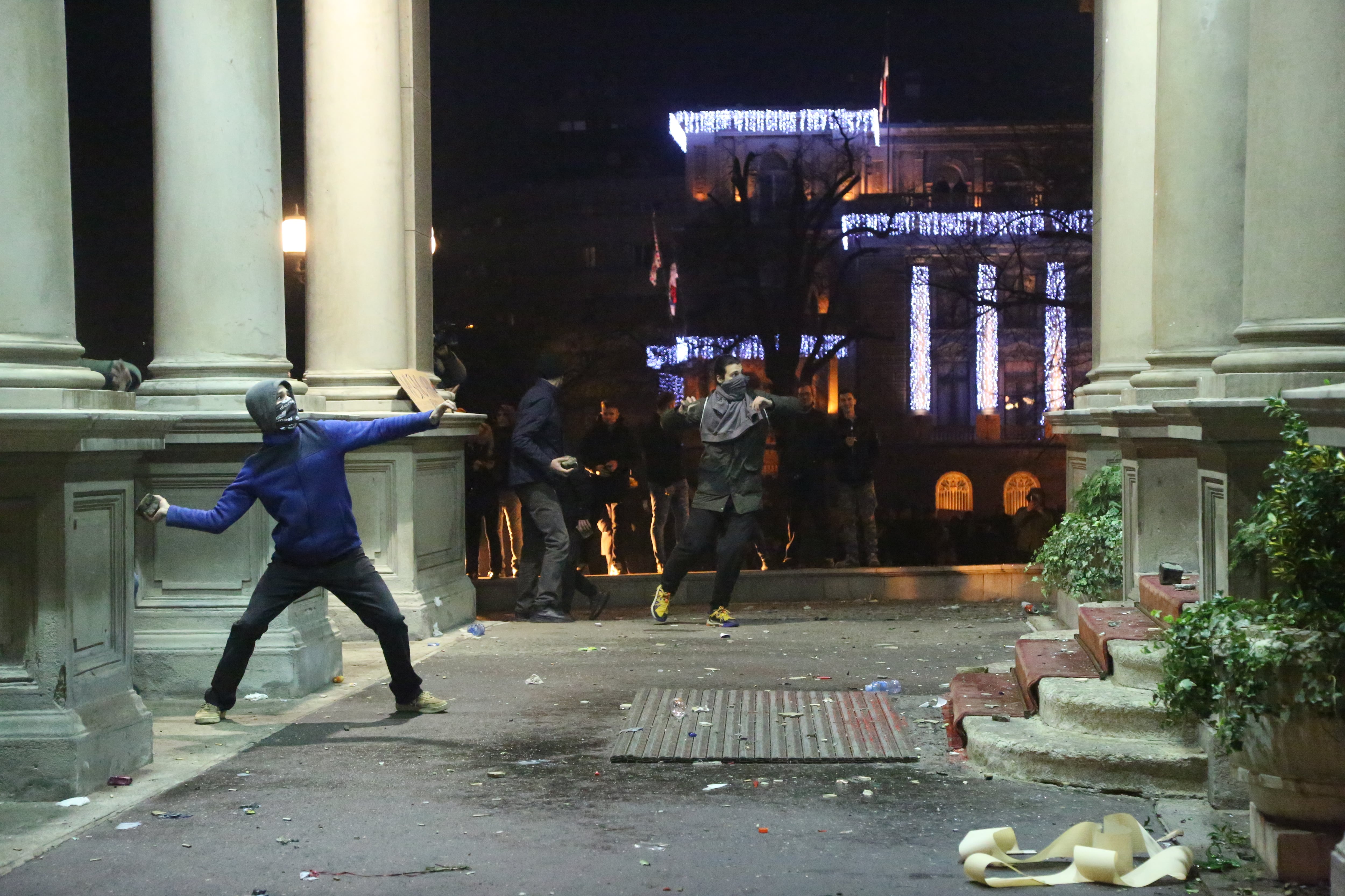 Un manifestante lanza una piedra durante las protestas de Nochebuena en Belgrado