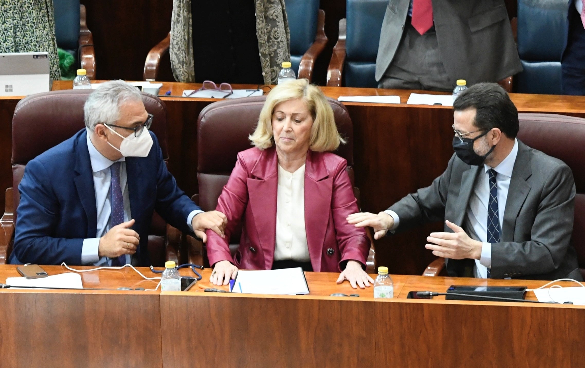 La consejera de Familia, Juventud y Política Social, Maria Concepción Dancausa (c), recibe el apoyo del consejero de Administración Local y Digitalización, Carlos Izquierdo (i), y del consejero de Economía, Hacienda y Empleo, Javier Fernández-Lasquetty (d)