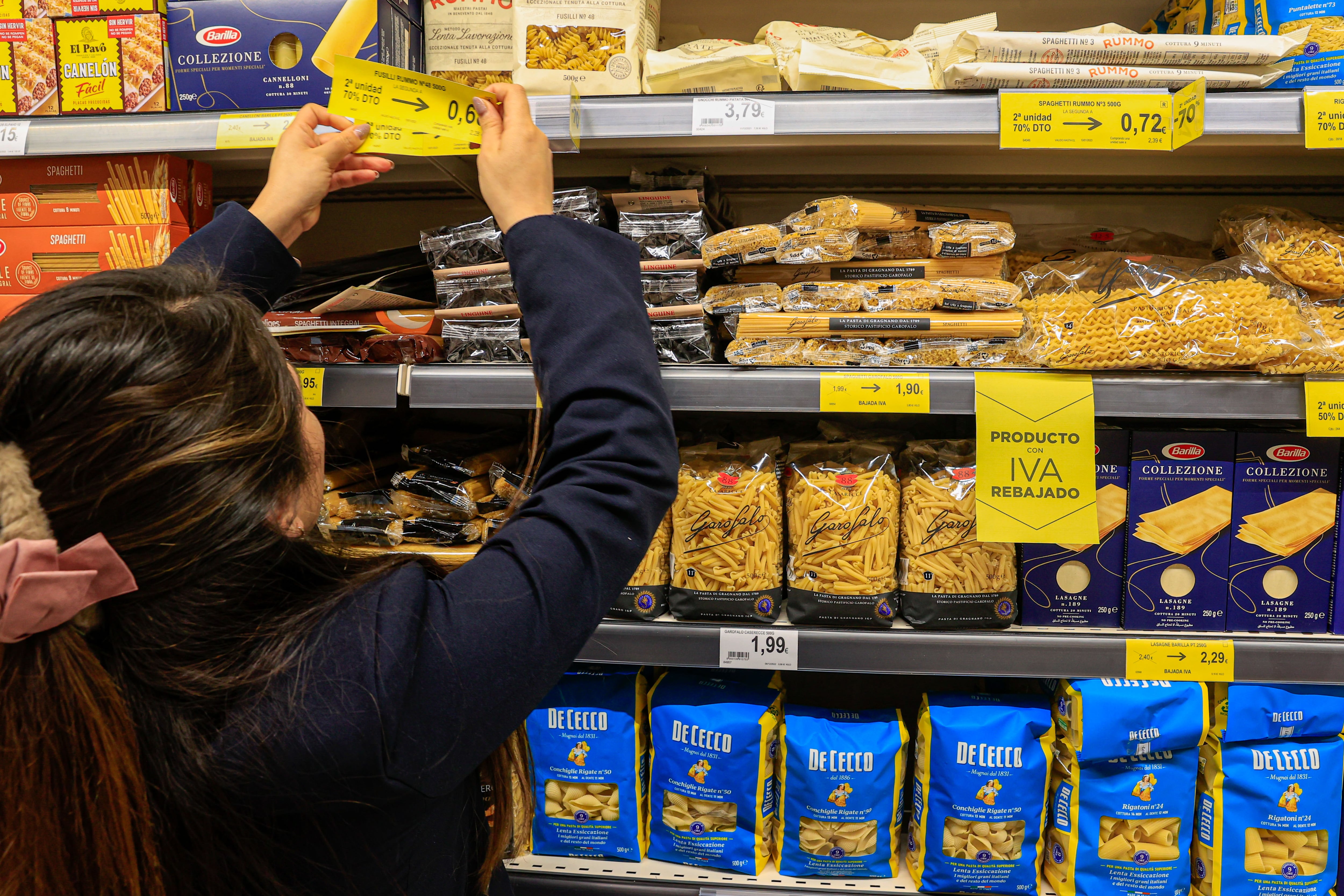 Los supermercados y tiendas de alimentación abren este lunes con los nuevos precios de los alimentos básicos sin IVA y del aceite y la pasta gravados al 5 %, una medida aprobada por el Gobierno en su última reunión de 2022 y que entra en vigor con el nuevo año. En la imagen, una empleada de   un supermercado de Madrid coloca los carteles con los nuevos precios.