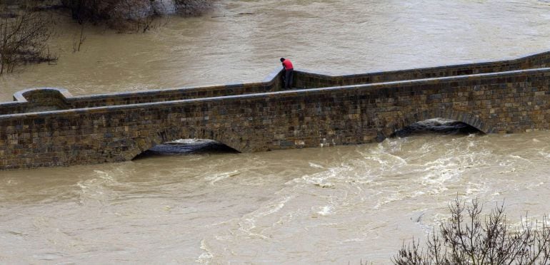Una persona observa el caudal del río Arga a su paso por la localidad navarra de Burlada.