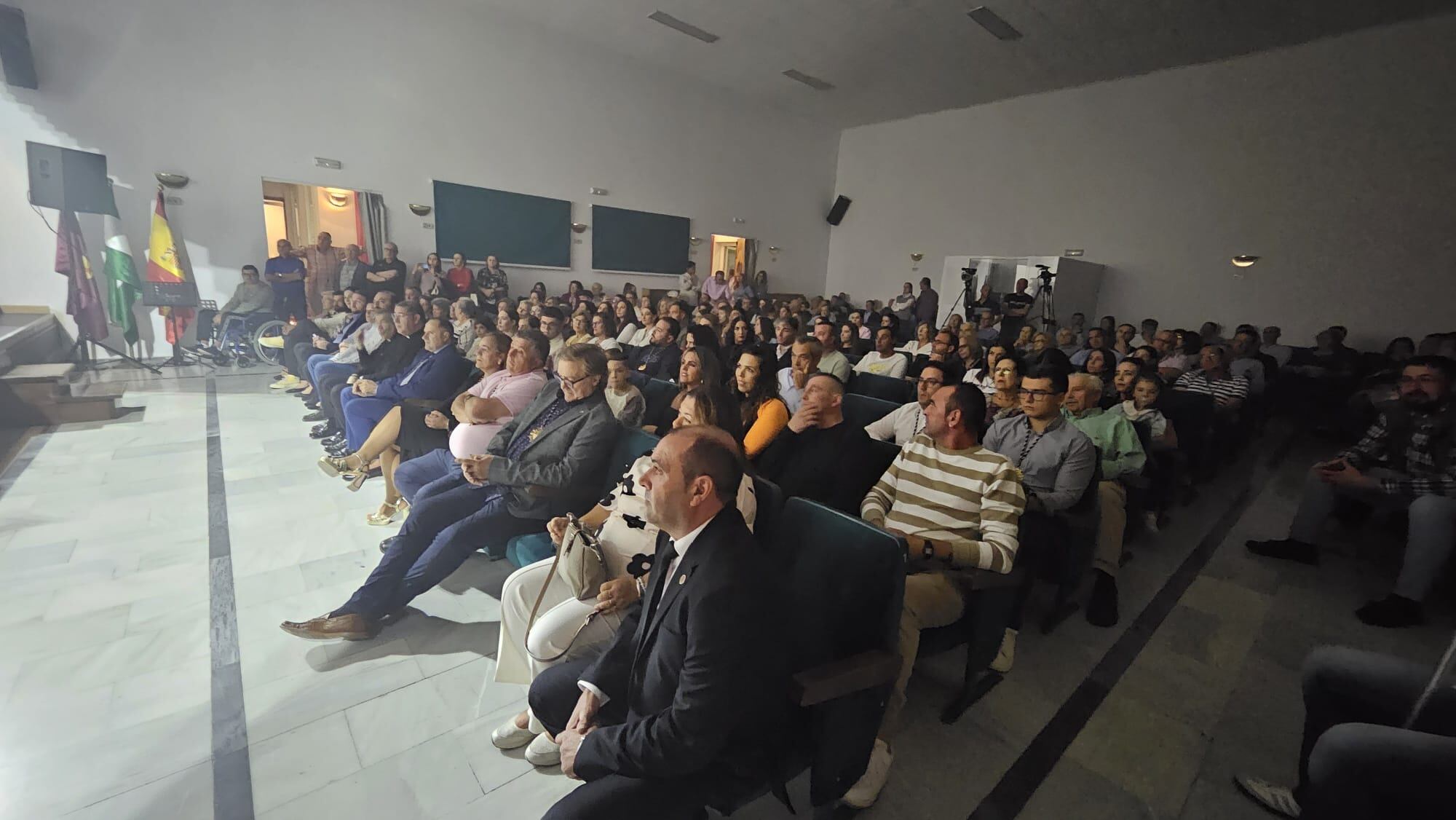 Público asistente, en el Salón de actos de la Casa de la Cultura, al pregón del Centenario de la Cofradía del Santo Entierro, con el pregonero en primer plano