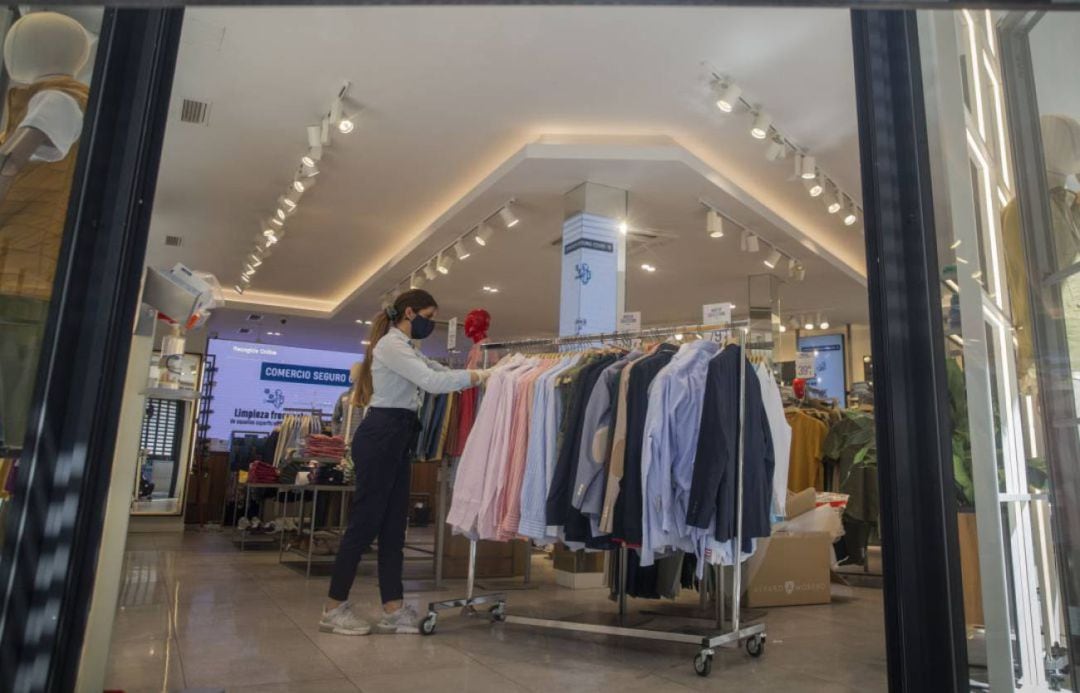 Una empleada de una tienda se prepara para la apertura del establecimiento