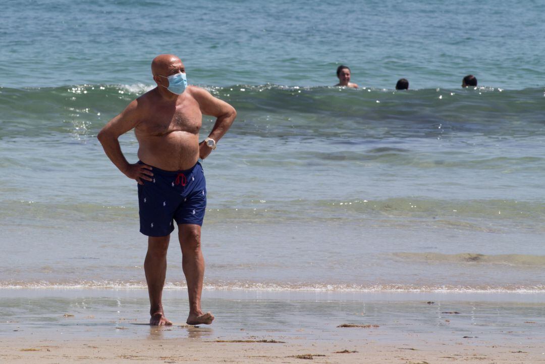 Un hombre protegido con mascarilla pasea por la Playa 