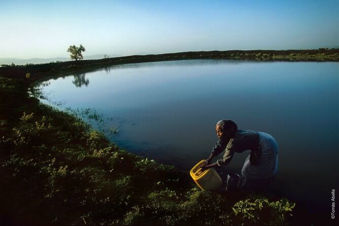 Una mujer coge agua en un lago en Etiopía preocupada por la presencia de hienas en los alrededores