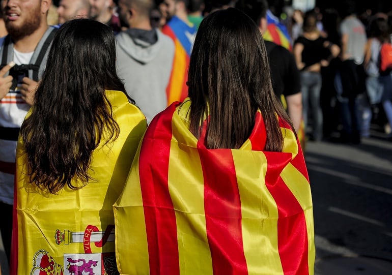 Dos chicas con banderas de España y Cataluña a la espalda