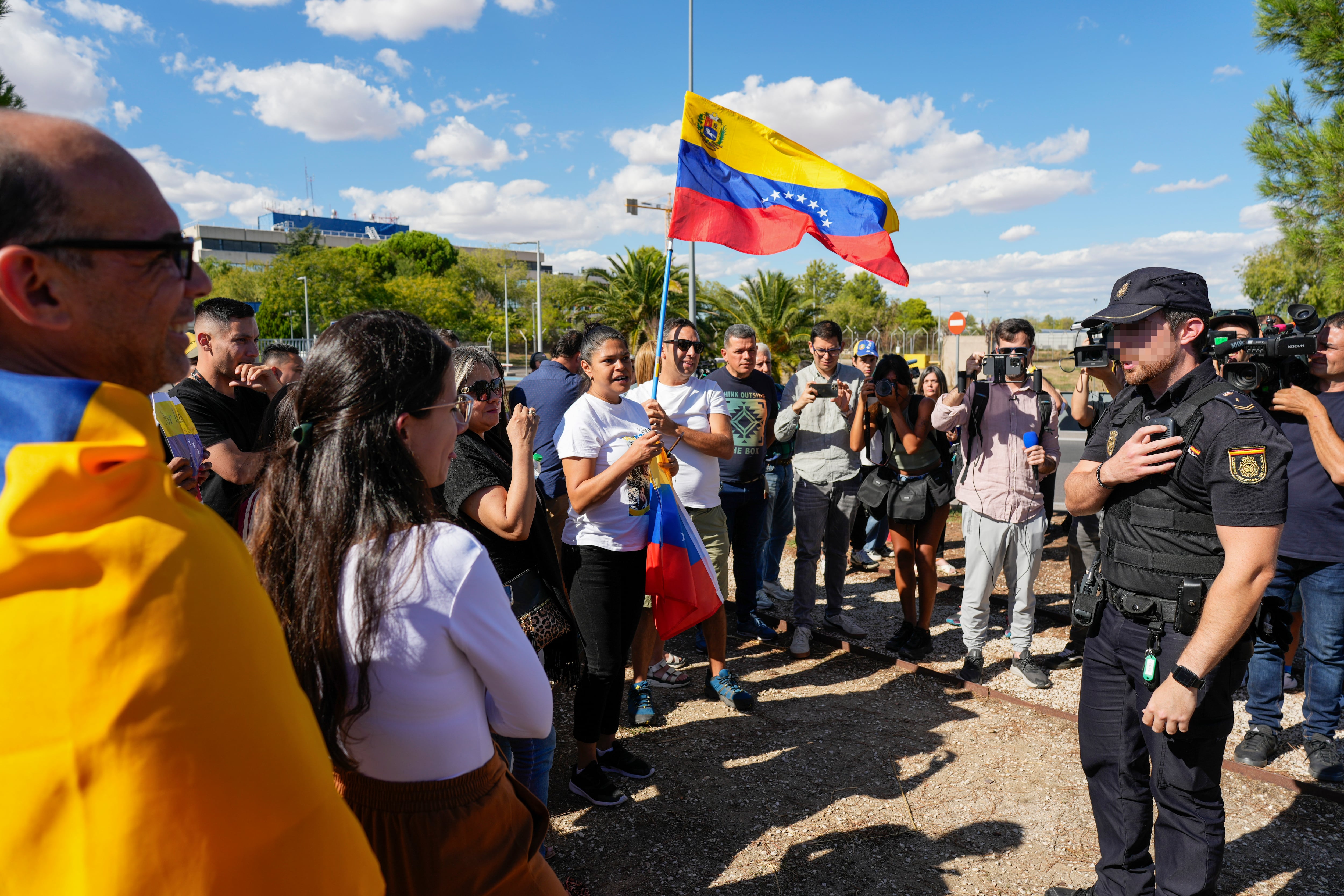 Simpatizantes del excandidato opositor a la Presidencia de Venezuela, Edmundo González Urrutia, conversan con un miembro de la Policía Nacional en la puerta de la base aérea de Torrejón de Ardoz (Madrid).