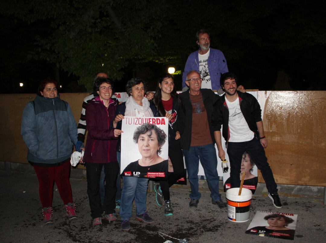 La candidata de IU, Montserrat Sanz sostiene uno de sus carteles junto con sus compañeros en la pegada de carteles de Cuéllar