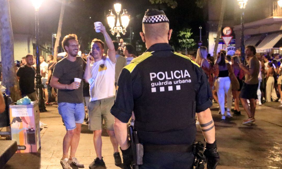 Un agente de la Guardia Urbana de Barcelona desaloja a personas que están realizando un botellón en el paseo del Born