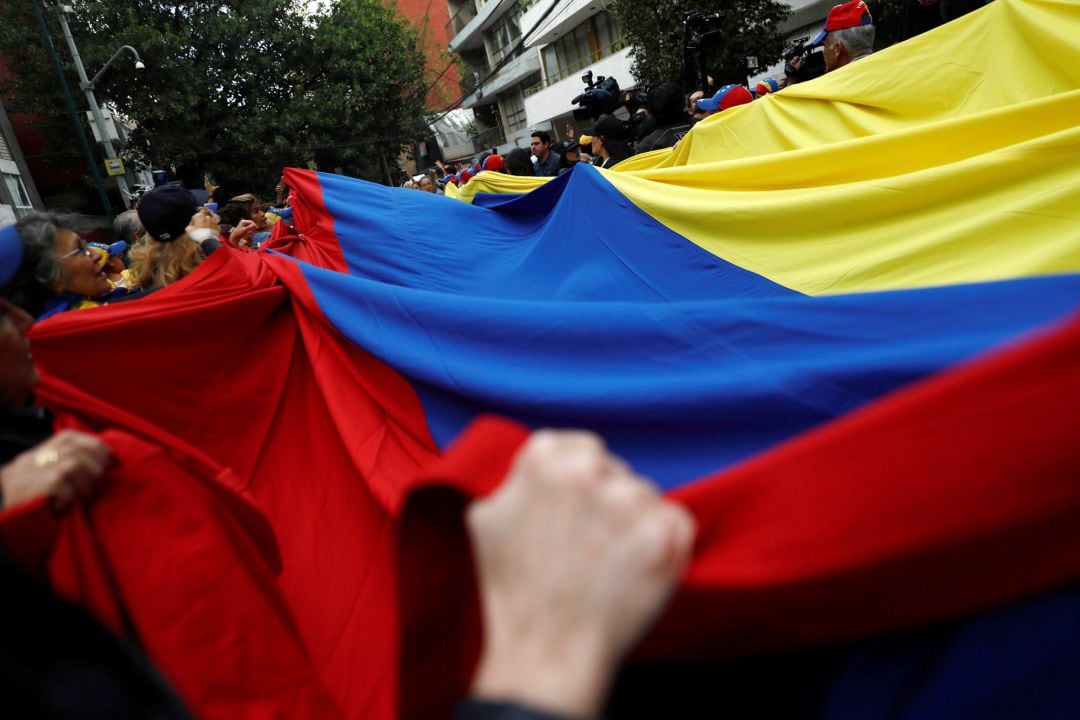  venezolanos sujetando una bandera durante las manifestaciones de los ultimos días 